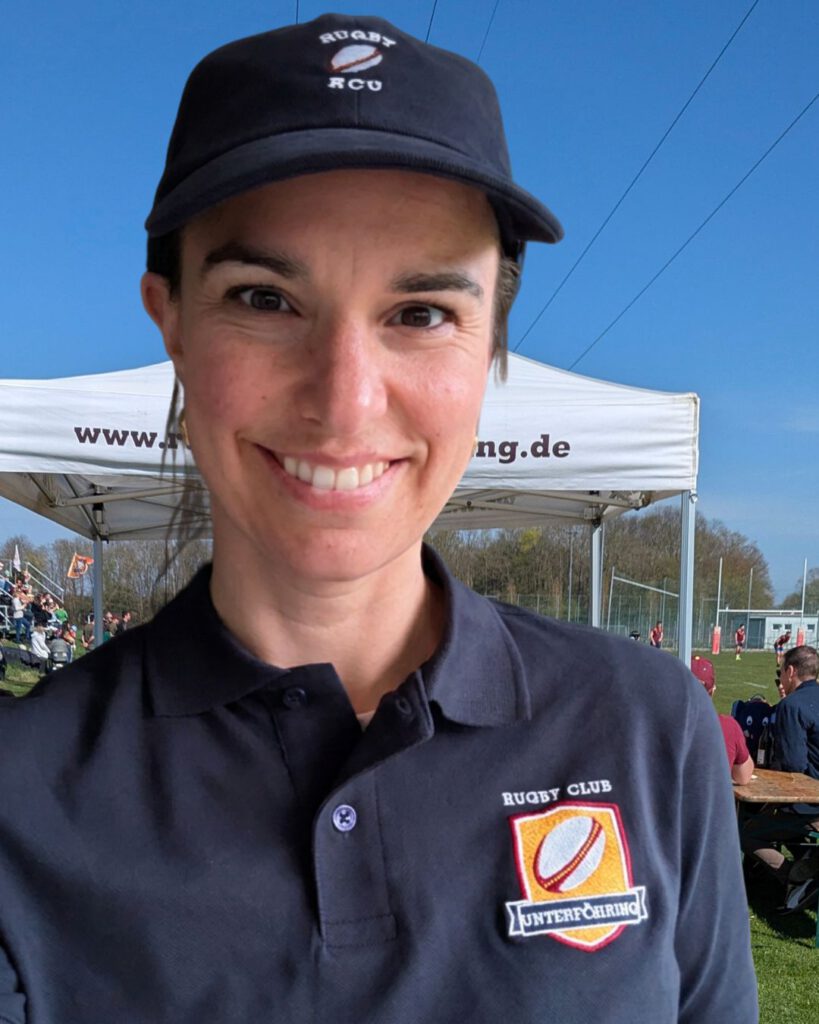 Eine Frau Mitte dreißig mit Cap und RCU Logo auf Poloshirt