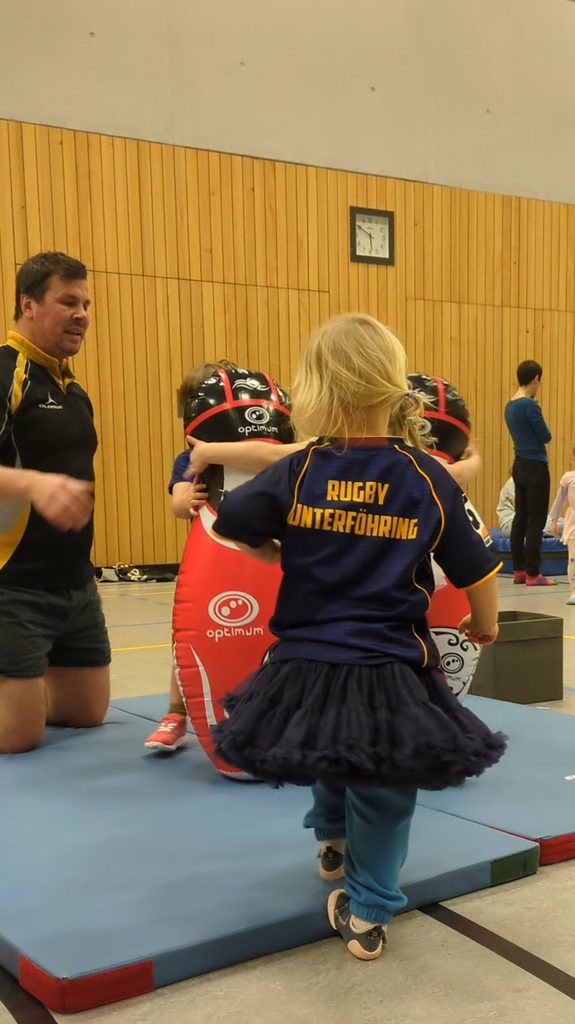 Ein kleines Mädchen trägt ein Rugby Trikot "Rugby Unterföhring" und dazu einen farblich passenden Ballett-Tut-Tut